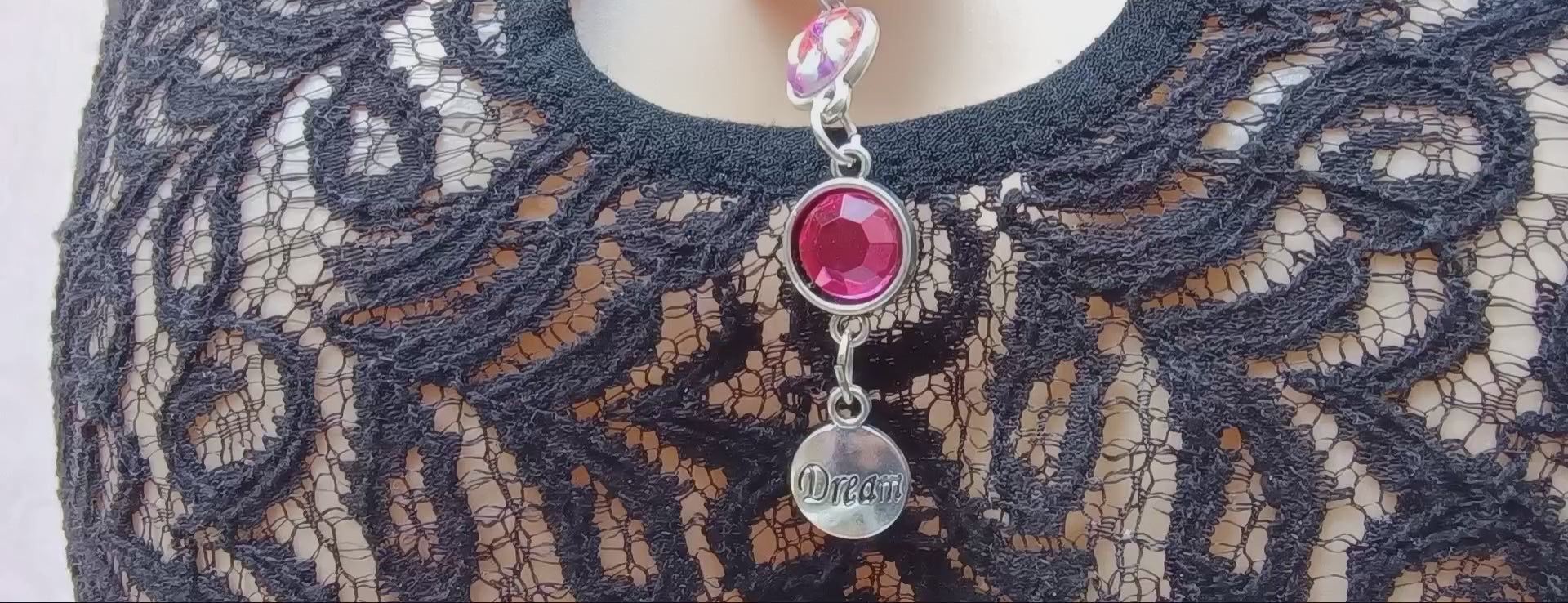 Load video: Short video showing lace back of bikini panties with keyhole detail and a pendant with a &#39;dream&#39; charm.